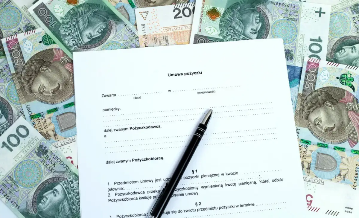 Umowa pożyczki na tle polskich banknotów. Szukasz informacji, gdzie pożyczki dla zadłużonych są dostępne? Dokument i pieniądze sugerują rozwiązanie.