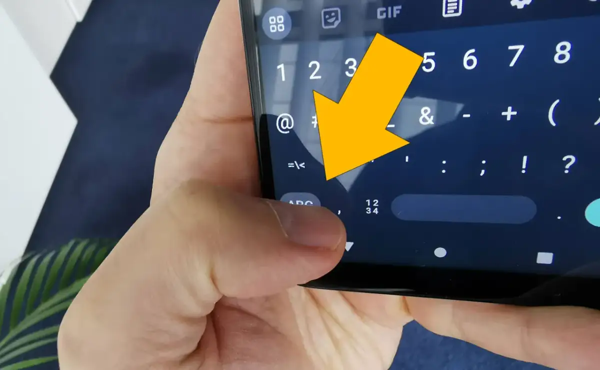 Żółta strzałka wskazuje na klawiaturę telefonu, na znak "<".