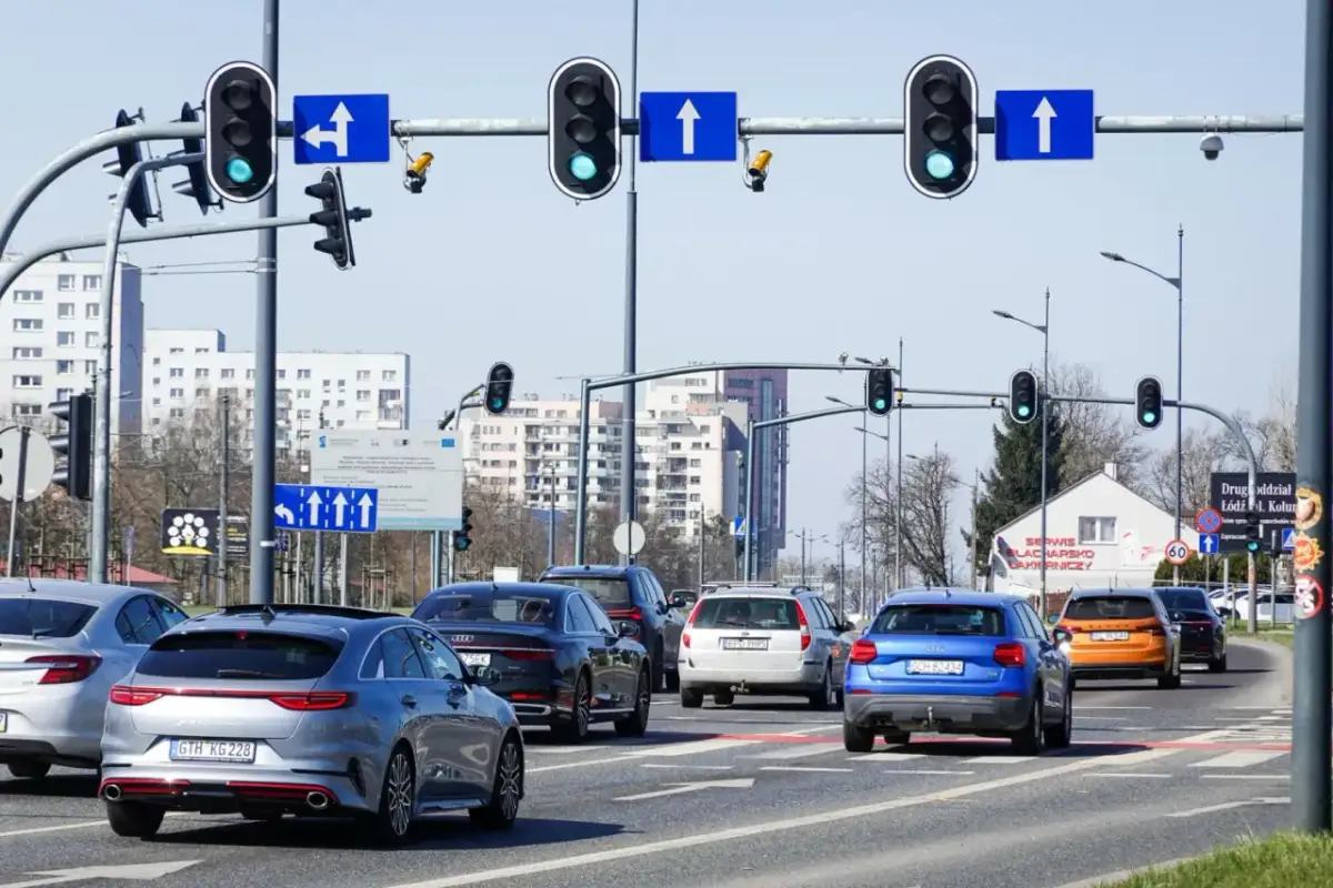 Na skrzyżowaniu z sygnalizacją świetlną, gdzie są kamery rejestrujące przejazd na czerwonym świetle, stoi kilka samochodów.