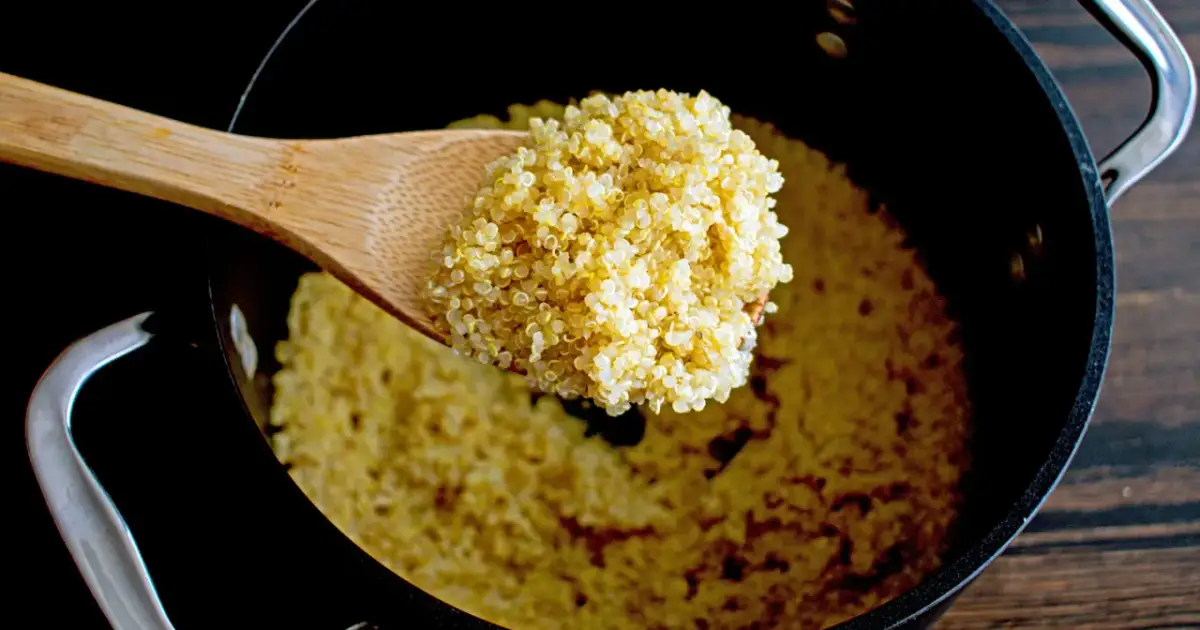Łyżka z ugotowaną komosą ryżową nad patelnią. Czy komosa ryżowa jest zdrowa? Tak, to świetne źródło białka i błonnika.
