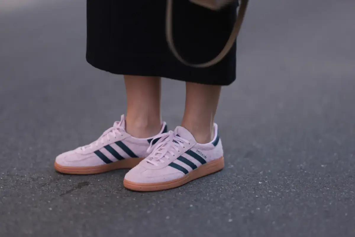Różowe buty sportowe Adidas z granatowymi paskami i brązową podeszwą.