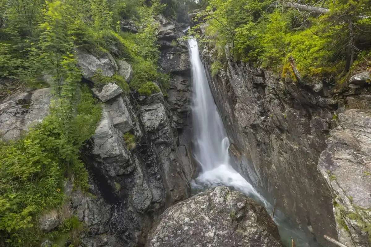 Wodospady na Słowacji w otoczeniu skalistych zboczy i bujnej zieleni. Woda spływa kaskadami po kamieniach.