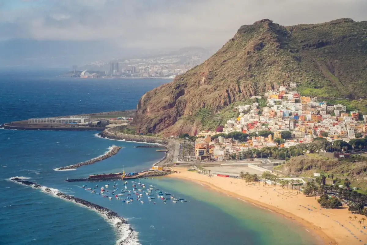 Kolorowe domki na zboczu góry nad plażą z łódkami. Czy to Teneryfa czy Fuerteventura?