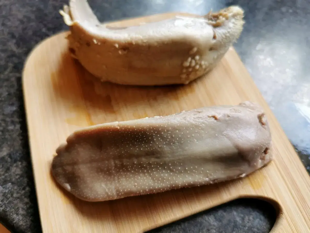 Dwa ugotowane ozory wieprzowe na desce. Zobacz, jak zdjąć skórę z ozora wieprzowego, by przygotować pyszne danie.