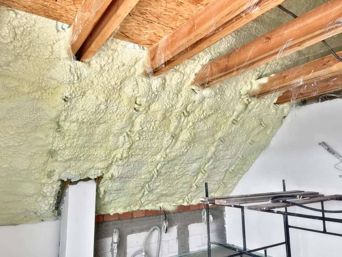 Poddasze ocieplone pianką, która szczelnie wypełnia przestrzeń między drewnianymi belkami. To nowoczesna pianka do ocieplenia poddasza.