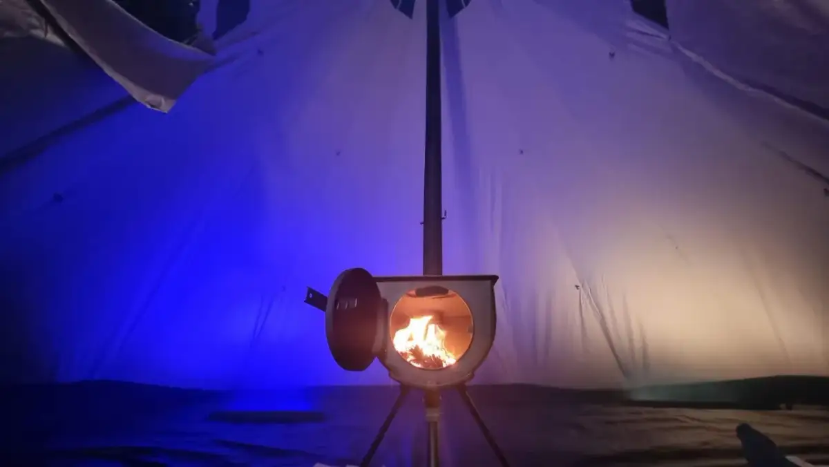 Wnętrze namiotu z palącym się piecykiem. To idealne ogrzewanie do namiotu, które tworzy przytulną atmosferę.