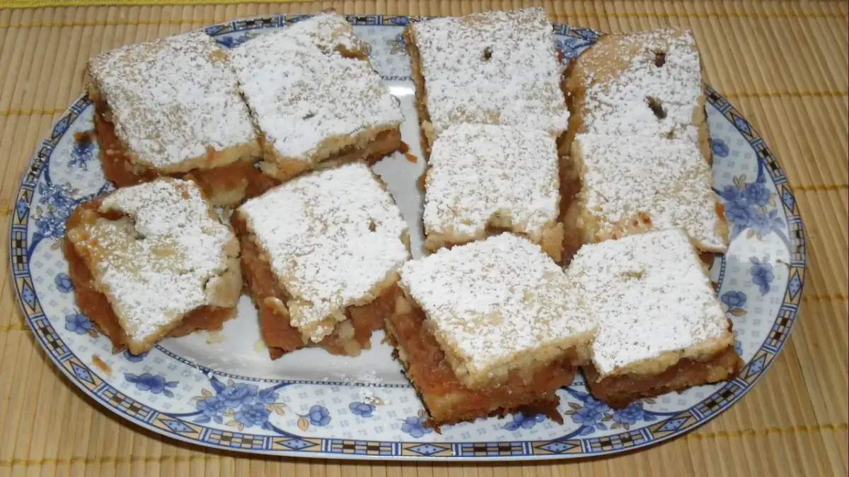 Na talerzu ułożono porcję 10 najlepszych ciast z jabłkami, posypanych cukrem pudrem.