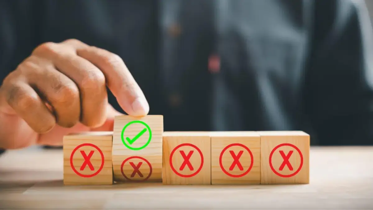 Dłoń wybiera klocek z zielonym zaznaczeniem spośród klocków z czerwonymi krzyżykami.