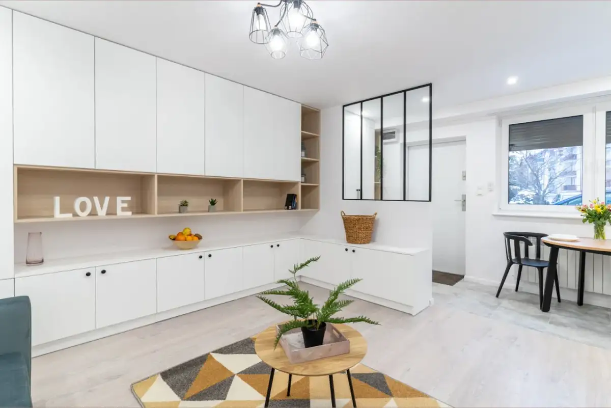 Nowoczesne wnętrze z białymi meblami na wymiar i drewnianymi wstawkami. Napis "LOVE" i kosz dodają ciepła. Idealne pakiety wykończenia pod klucz.