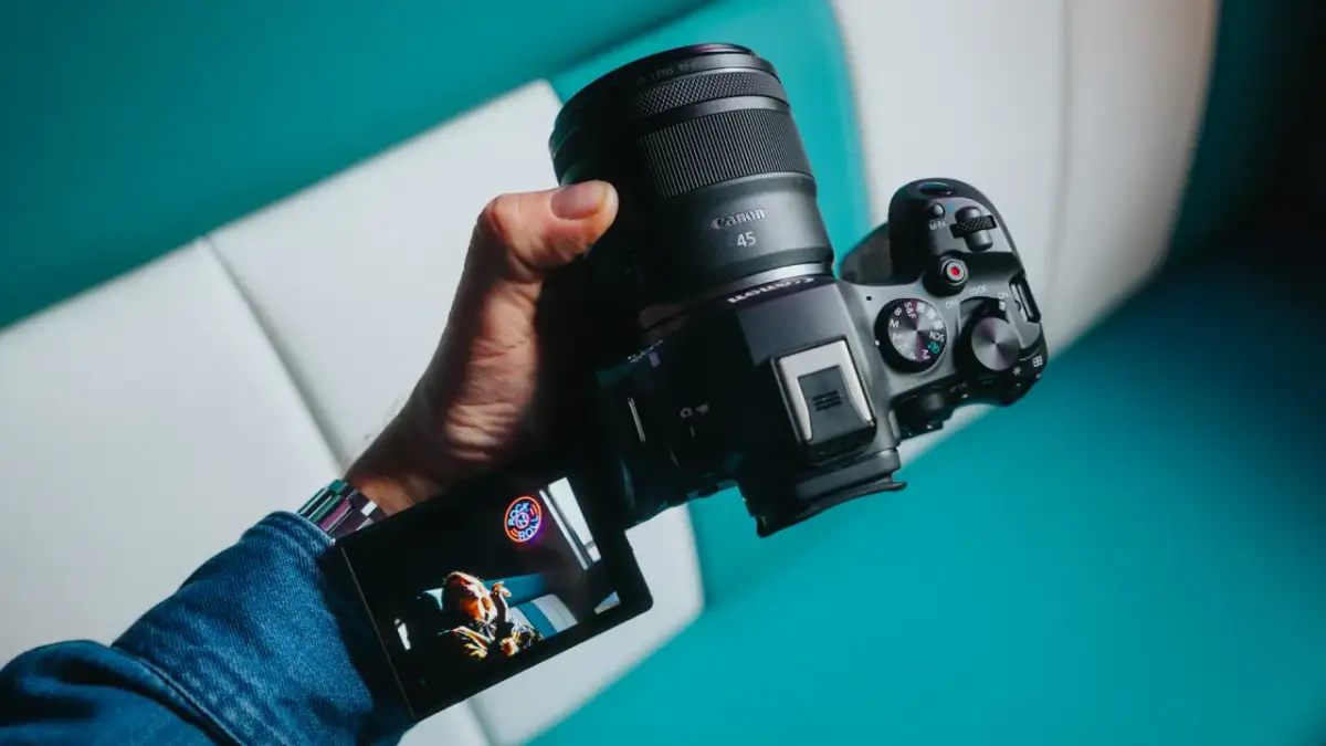 Dłoń trzyma aparat Canon z obiektywem RF 45mm. Wyświetlacz pokazuje zdjęcie.