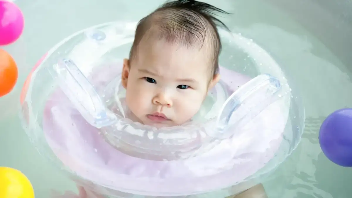 Urocze niemowlę w okrągłym kole do pływania dla niemowląt, otoczone kolorowymi zabawkami.