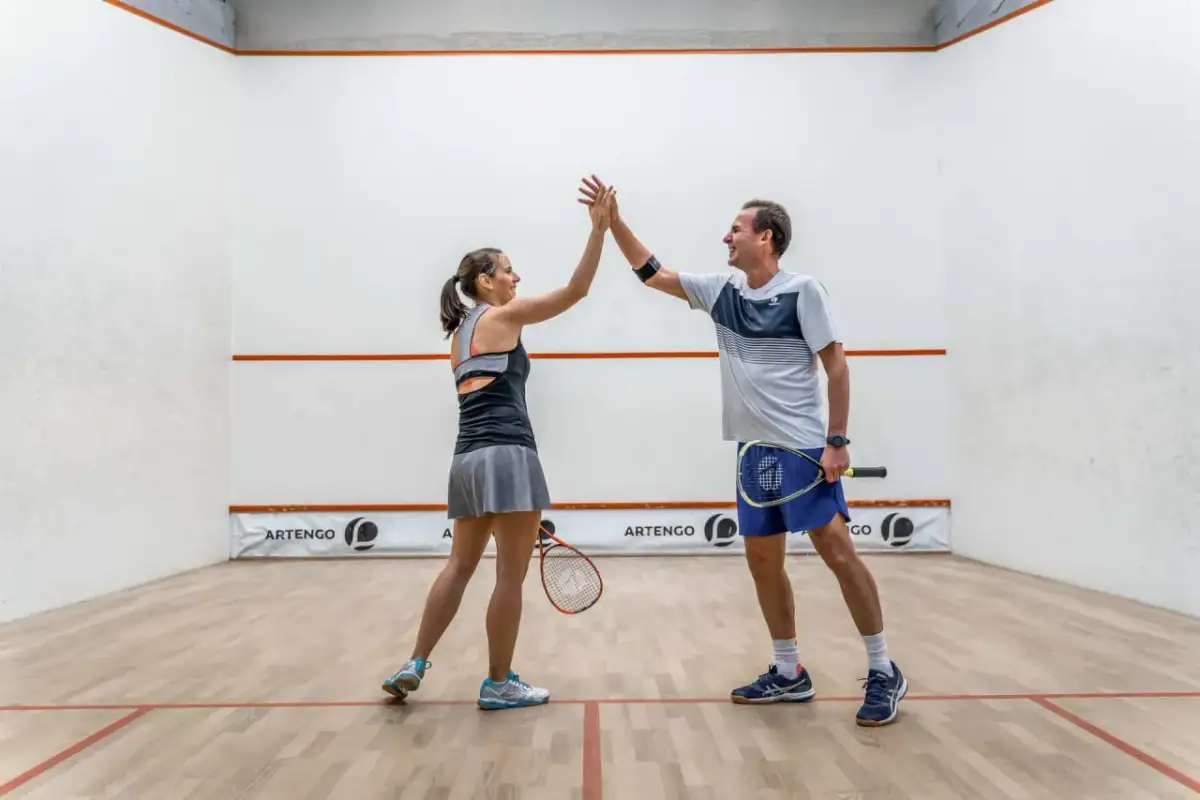 Para grająca w squasha daje sobie piątkę na korcie.