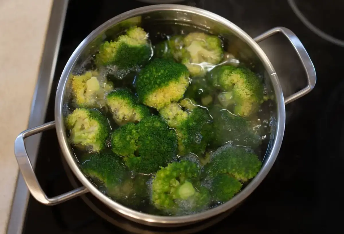 Zielone różyczki brokułów gotują się w garnku, przygotowywane do sałatki.