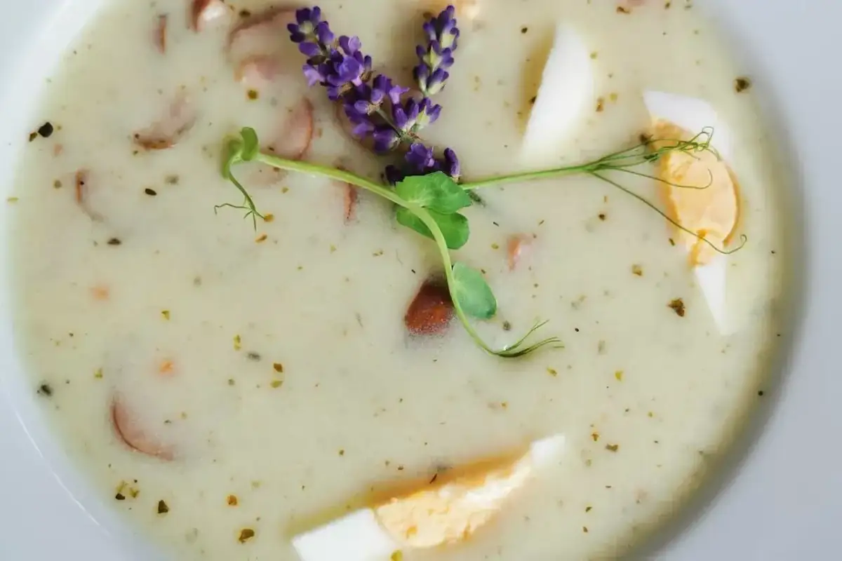 Pyszny żurek z kiełbasą i jajkiem, ozdobiony ziołami. Czy w ciąży można jeść żurek? Tak, ale z umiarem i zależy od składników.