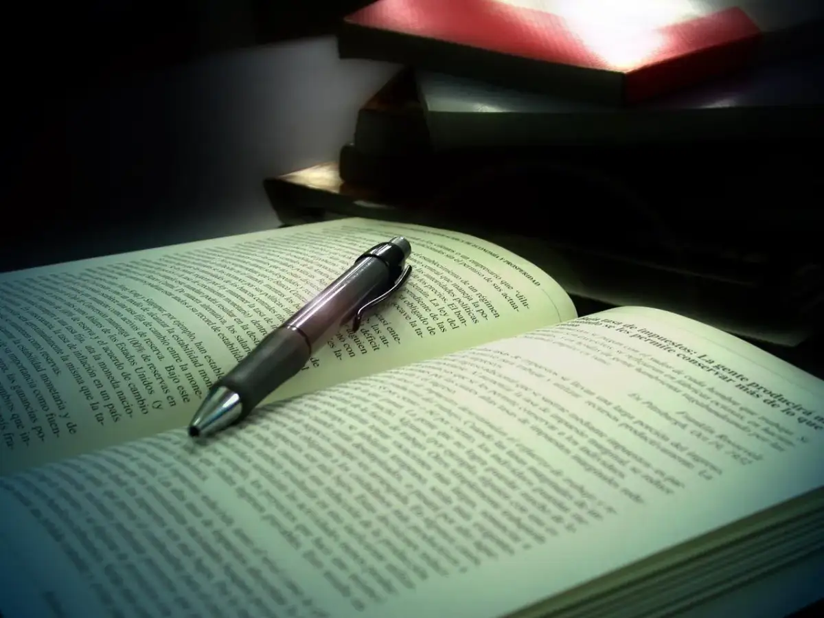 Otwarta księga z długopisem, jakby ludzie którzy szli, zatrzymali się, by coś przeczytać.