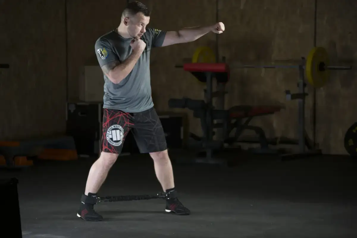 Mężczyzna ćwiczy w siłowni, wykonując ciosy. To świetny przykład, jak trening HIIT co to jest, może być efektywny.