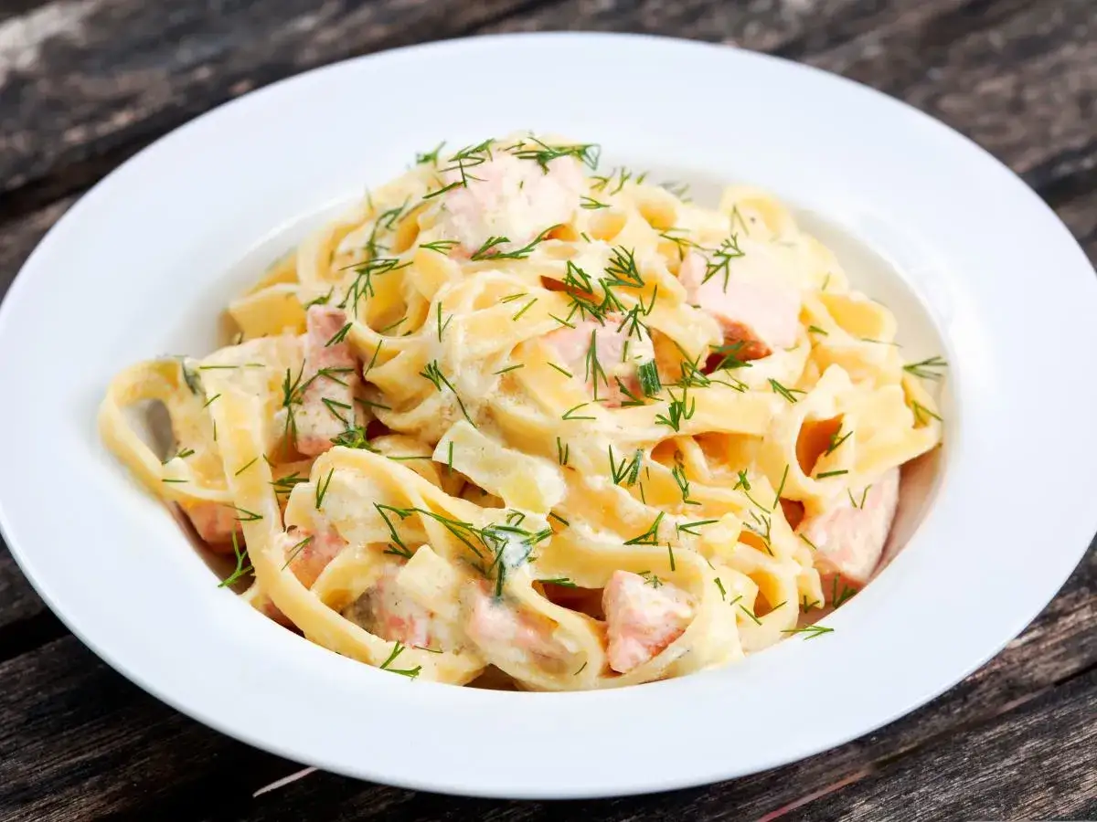 Pyszny makaron z łososiem w kremowym sosie, posypany świeżym koperkiem. Idealny na obiad.
