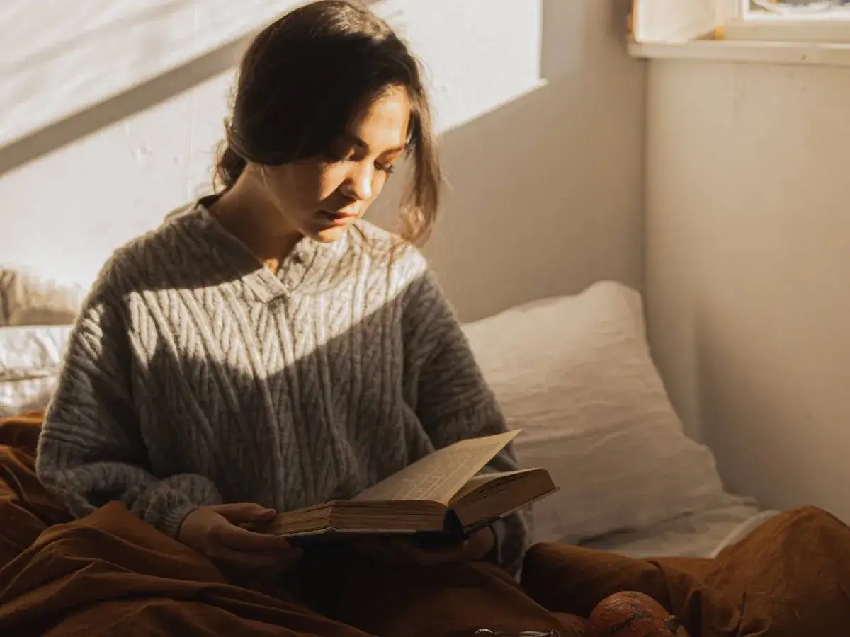 Dziewczyna w swetrze czyta książkę, pogrążona w myślach. Czy to irracjonalizm co to, czy głęboka refleksja?