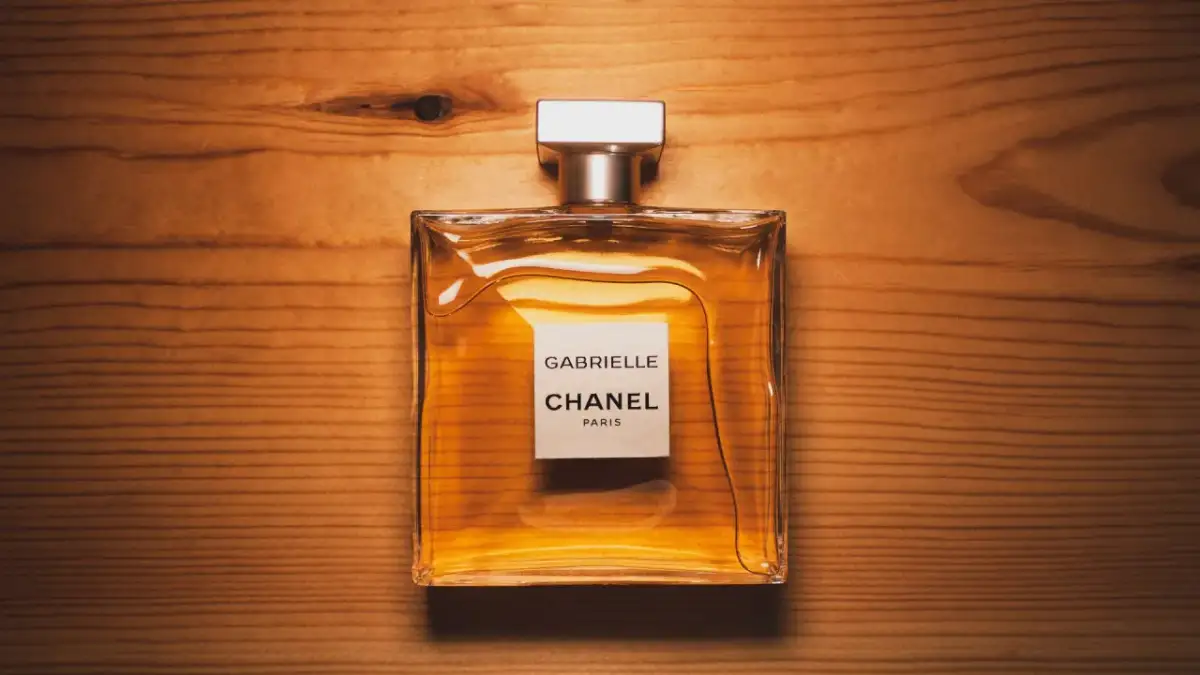 Eleganckie perfumy Gabrielle Chanel Paris w szklanej butelce na drewnianym tle.