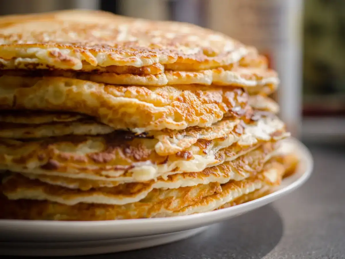 Stos racuchów na białym talerzu, złociste i puszyste.