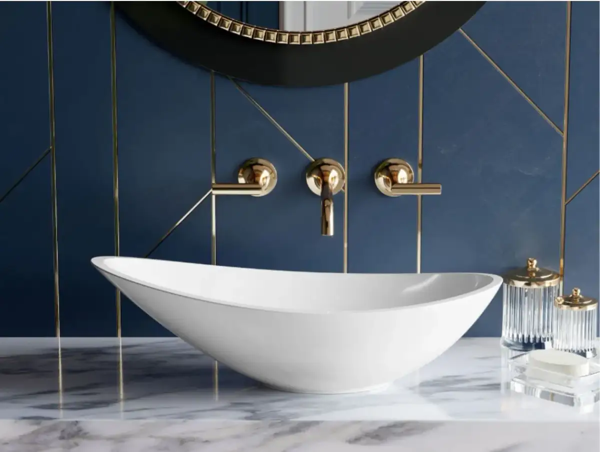 Elegancka, biała umywalka na nodze w łazience z granatową ścianą i złotymi detalami.