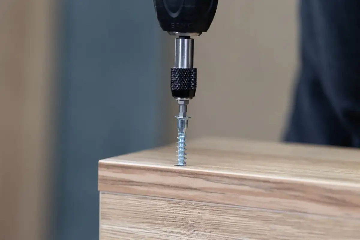 Wkrętarka wkręca wkręt w drewniany mebel.