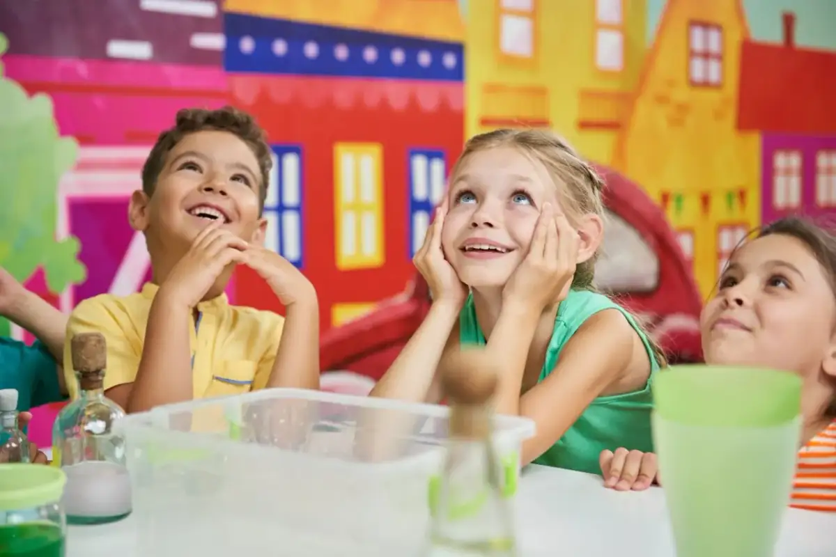 Uśmiechnięte dzieci patrzą w górę, jakby słuchały zabawnych historii. Idealne na kawały dla dzieci od 5 lat.