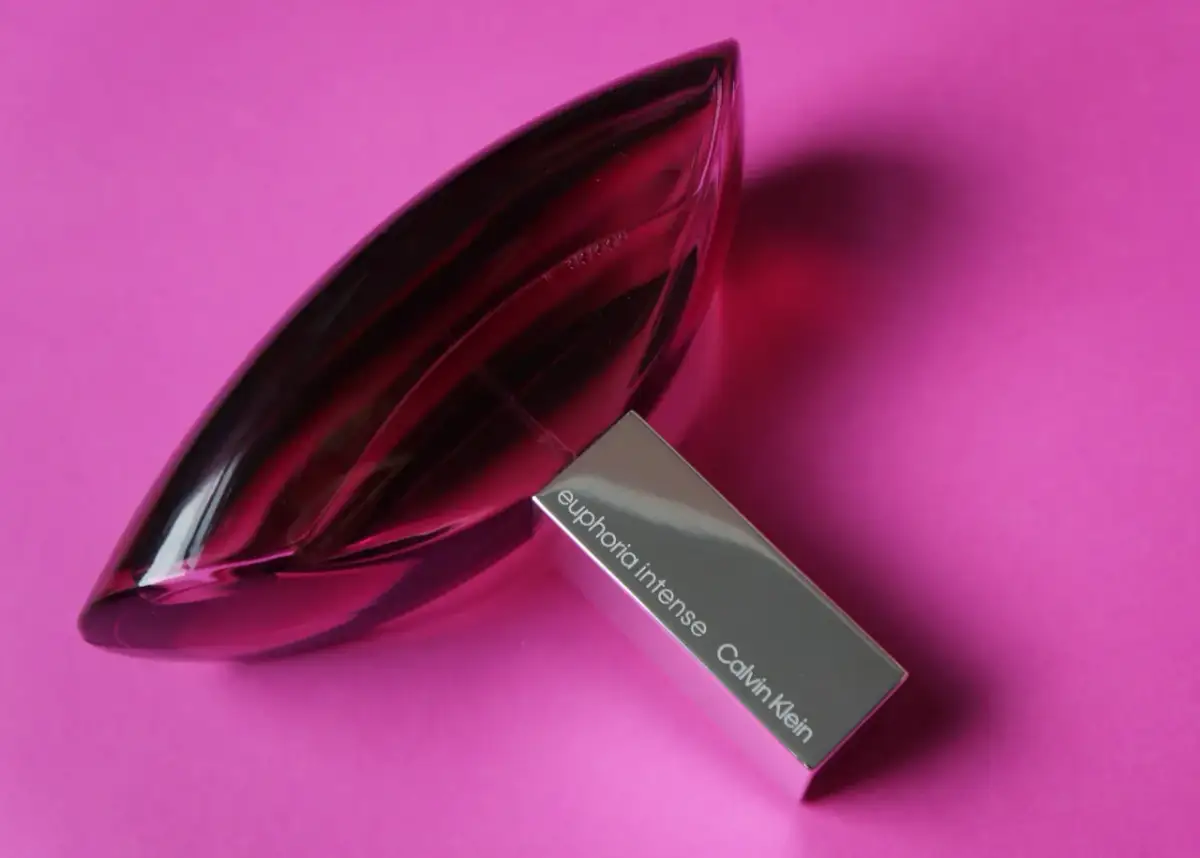 Różowa butelka Euphoria Intense Calvin Klein, woda perfumowana, lśni na tle intensywnego różu.