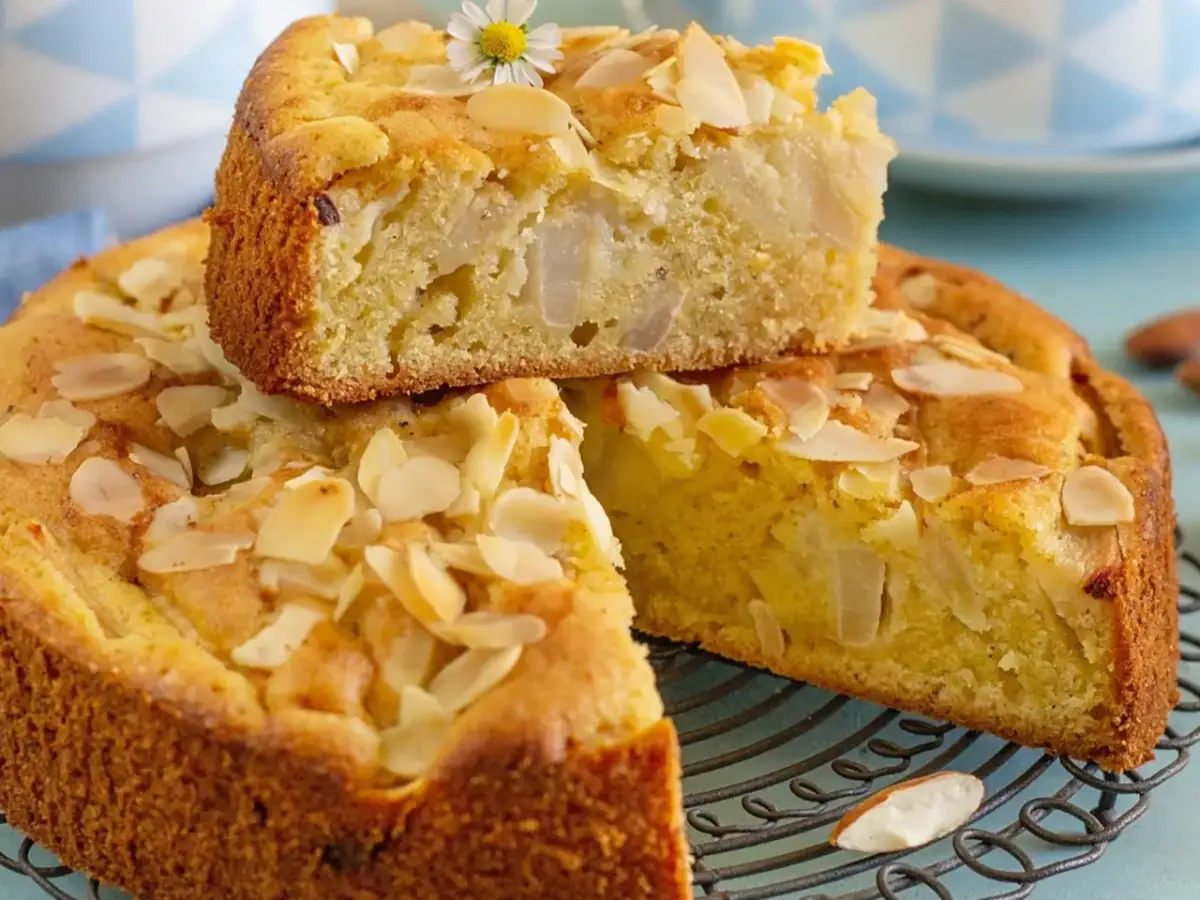 Pyszne ciasto z gruszkami, posypane płatkami migdałów i ozdobione małym kwiatkiem. Idealne na deser.