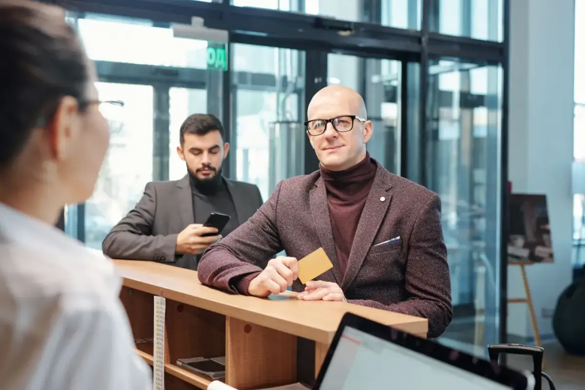 Mężczyzna z kartą w ręku, spełniający wymagania private banking, czeka przy ladzie.