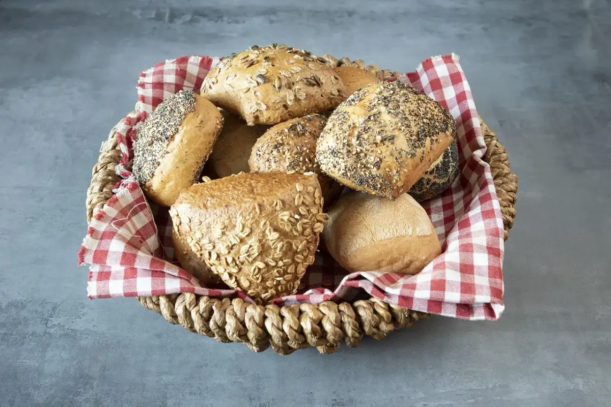 Kosz pełen bułek z ziarnami i płatkami owsianymi. Czy bułki są zdrowe? Te wyglądają apetycznie i bogato w składniki odżywcze.