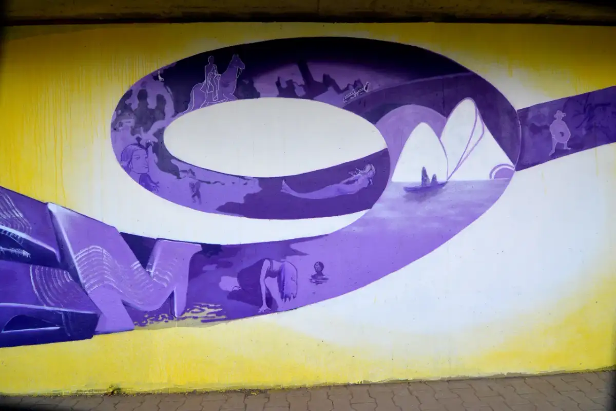 Graffiti-Wandmalerei mit lila 3D-Buchstaben und Szenen wie Reiter, Meerjungfrau und Boot.