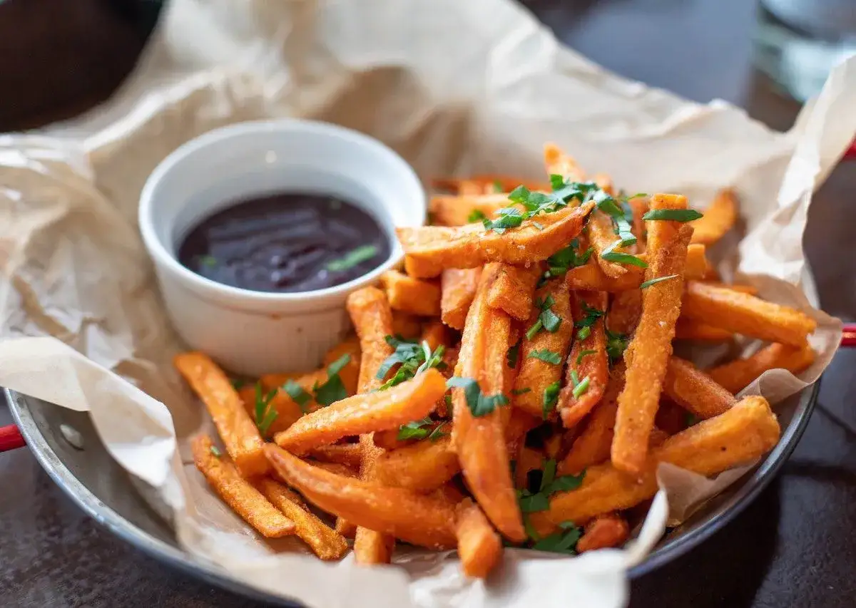 Chrupiące frytki z batatów, posypane natką pietruszki, podane z sosem BBQ. Idealne, gdy zastanawiasz się, jak odgrzać frytki, by znów były pyszne.