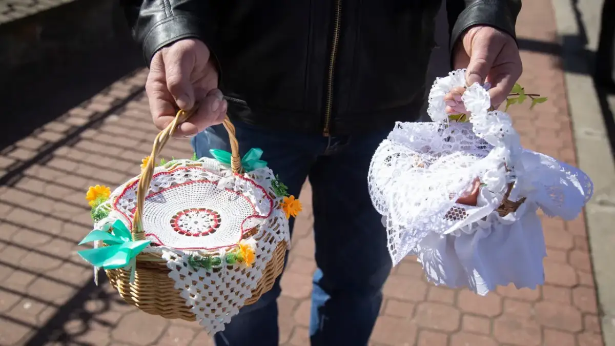 Dwie ozdobne koszyczki do święconki, jeden z koronką i kwiatkami, drugi przykryty białą tkaniną.