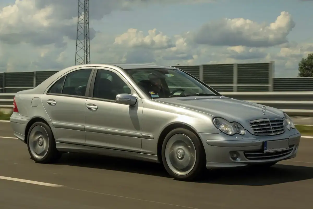 Srebrny Mercedes W203 2.2 CDI pędzi autostradą, chmury na niebie tworzą ciekawe kształty.