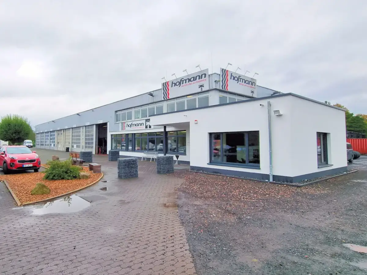 Gebäude von Reifen Hofmann Bebra mit roten Auto davor.