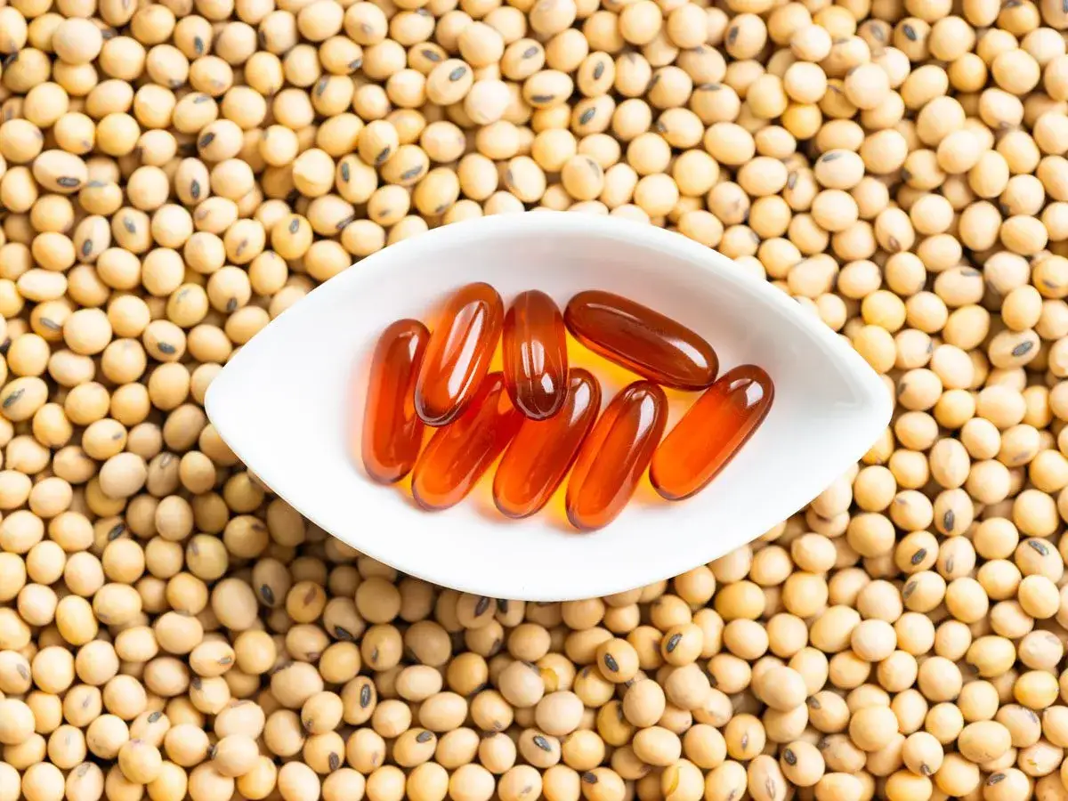 Kapsułki z lecytyną sojową na tle ziaren soi. Czy lecytyna sojowa jest szkodliwa?