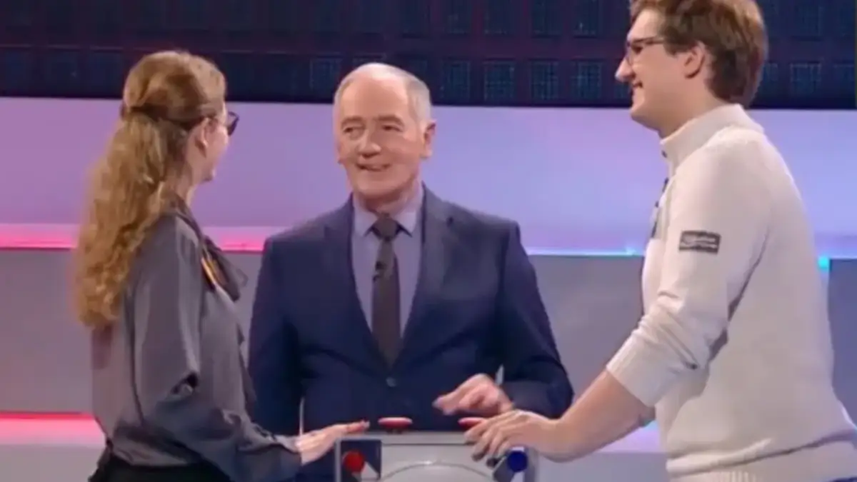 Trzy osoby na planie teleturnieju Familiada: prowadzący i dwoje uczestników.
