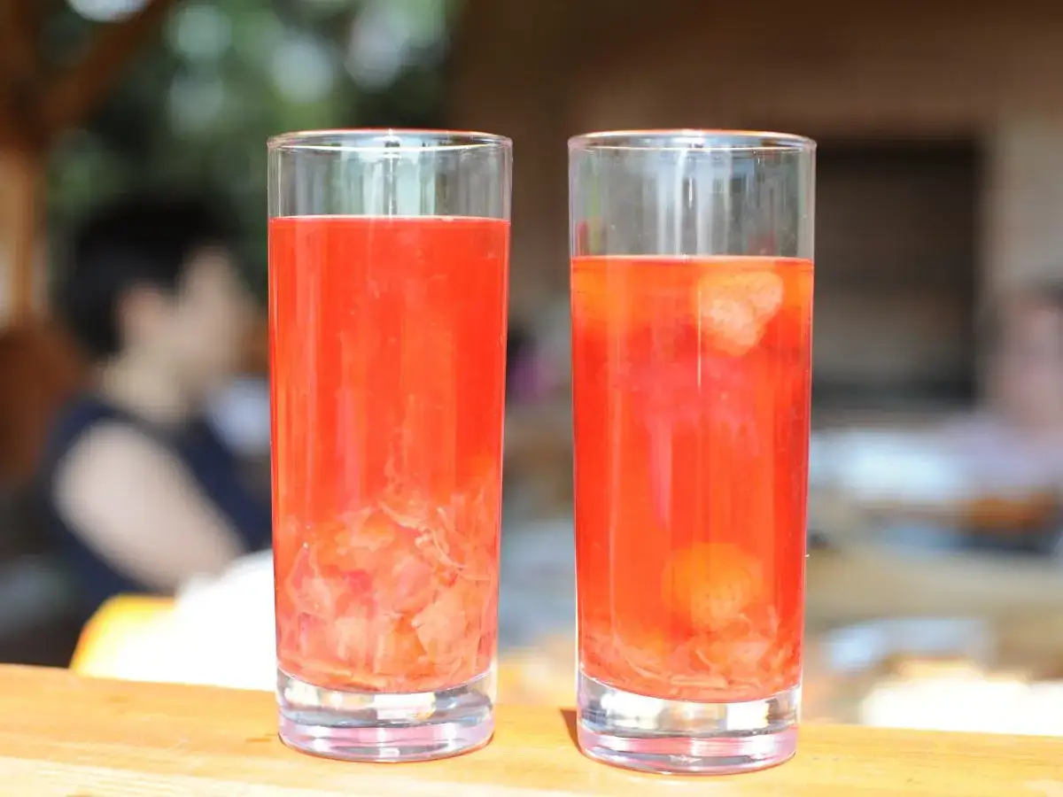 Dwa szklanki orzeźwiającego kompotu z rabarbaru, z widocznymi kawałkami owoców i truskawek. Idealny na letnie popołudnie.