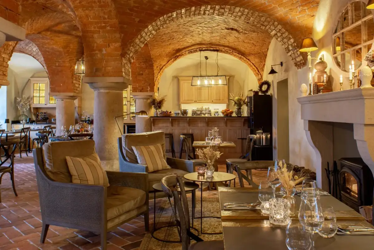 Wnętrze restauracji z ceglanymi łukami, kominkiem i stołami.