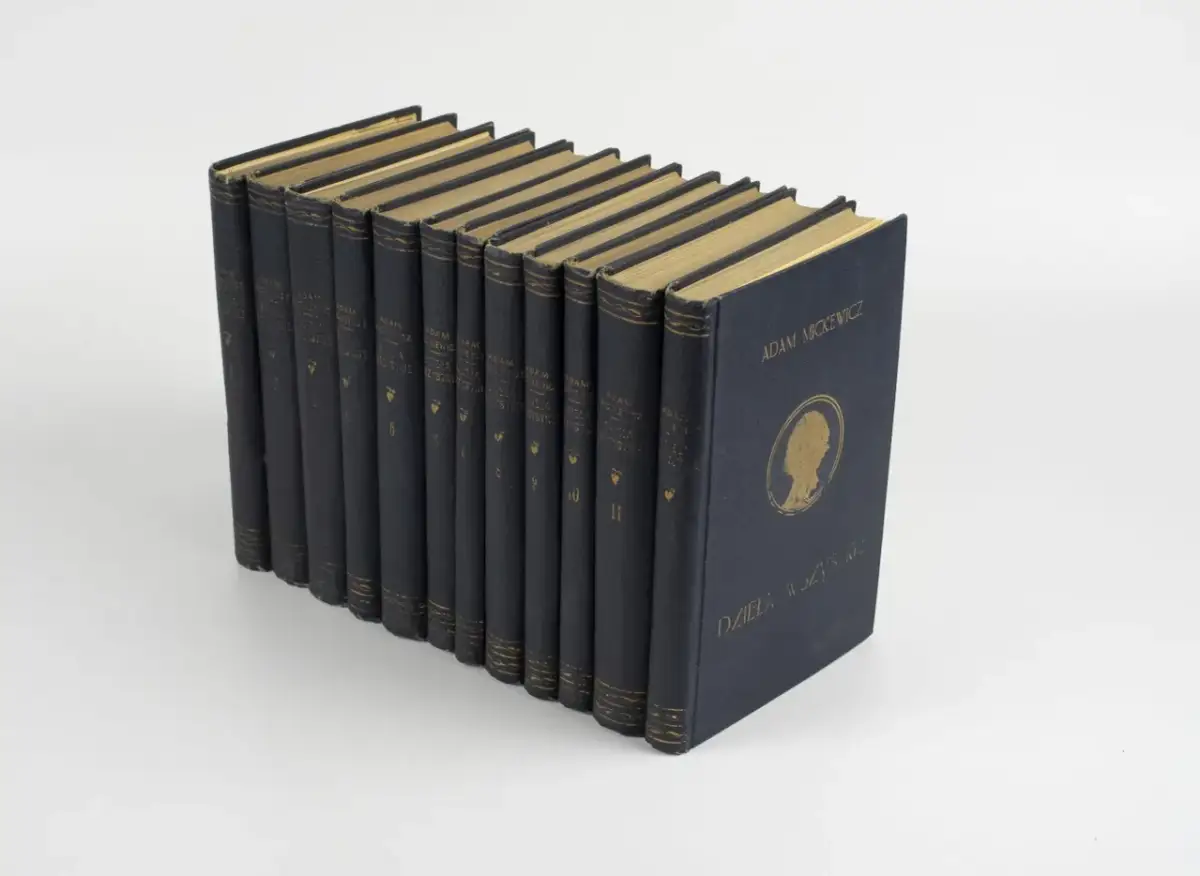 Złocone grzbiety książek z napisem "Adam Mickiewicz Dzieła Wszystkie" świadczą o bogactwie jego twórczości.