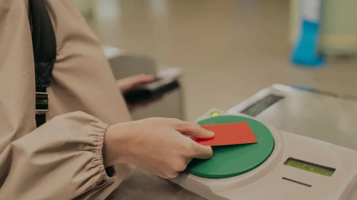 Ręka zbliża czerwoną kartę do czytnika. To może być karta Multisport, która otwiera drzwi do aktywności.