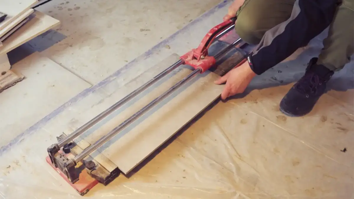 Ręce trzymające płytkę gresową na przecinarce do płytek.