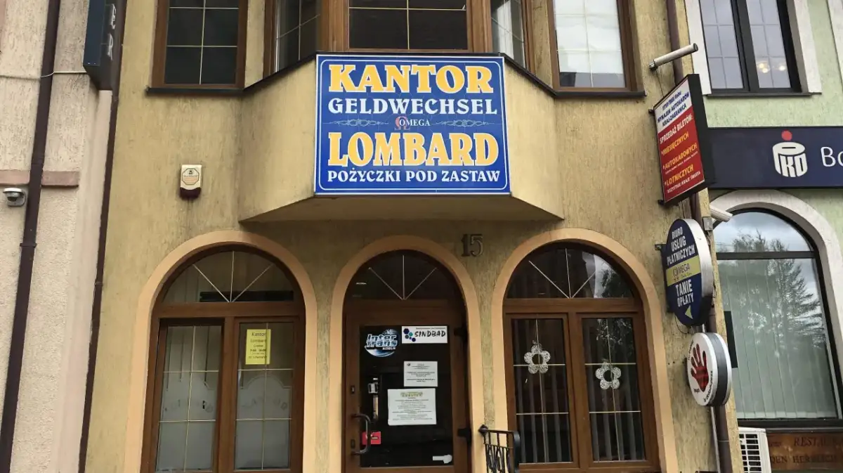 Elewacja budynku z szyldem "KANTOR GELDWECHSEL LOMBARD POŻYCZKI POD ZASTAW".