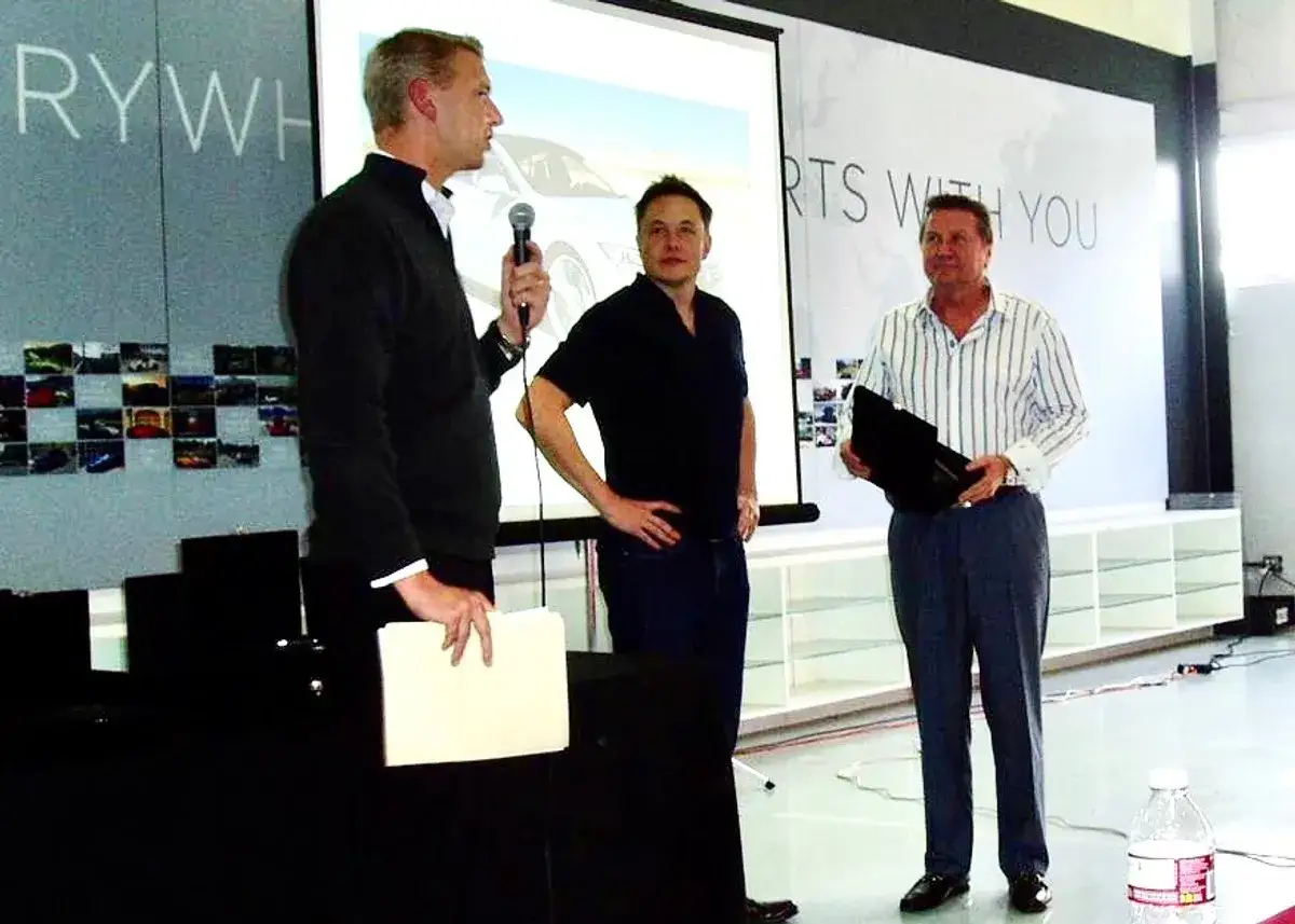 Elon Musk, jeden z tych, kto stworzył Teslę, stoi obok dwóch mężczyzn podczas prezentacji.