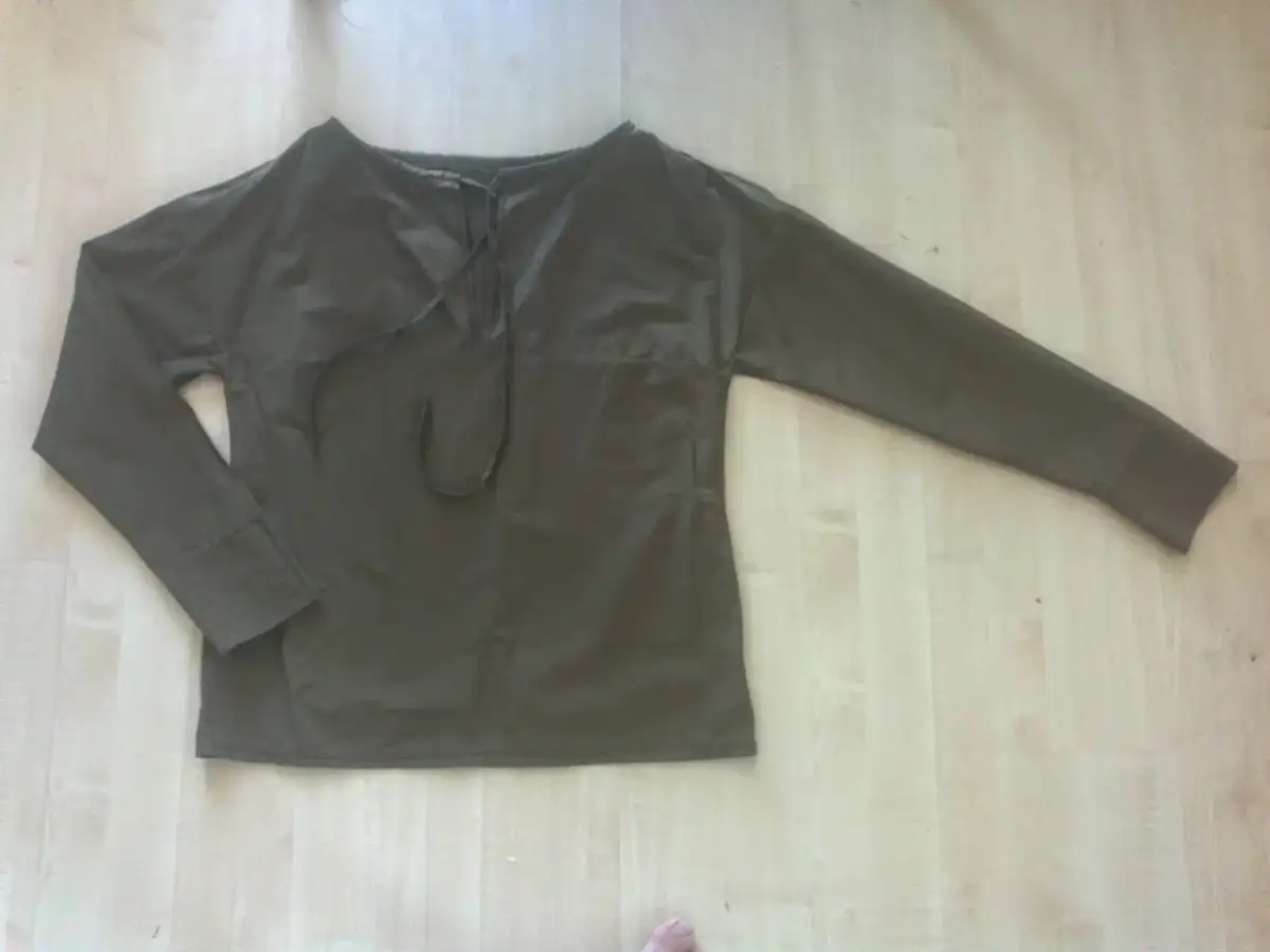 Gotowa bluzka z długim rękawem, uszyta z ciemnej tkaniny, z ozdobnym sznurowaniem przy dekolcie.