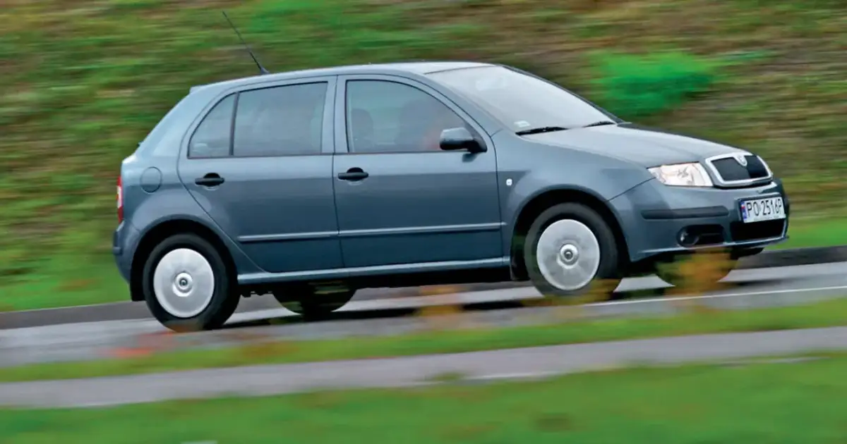 Szara Skoda Fabia 1 w ruchu, z rozmytym tłem zieleni i drogi.