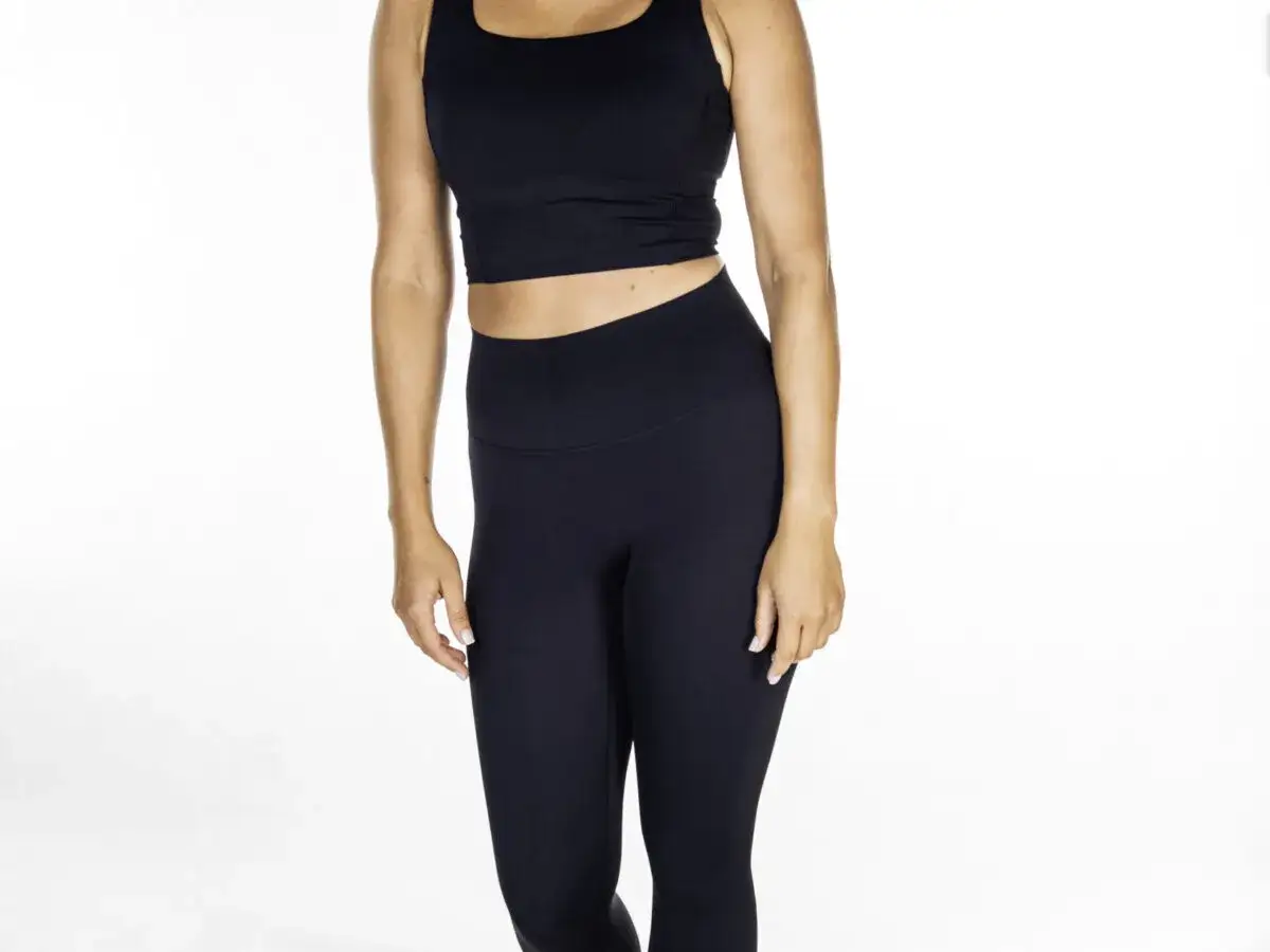 Kobieta w czarnym sportowym topie i dopasowanych legginsach do pływania, gotowa na wodne aktywności.