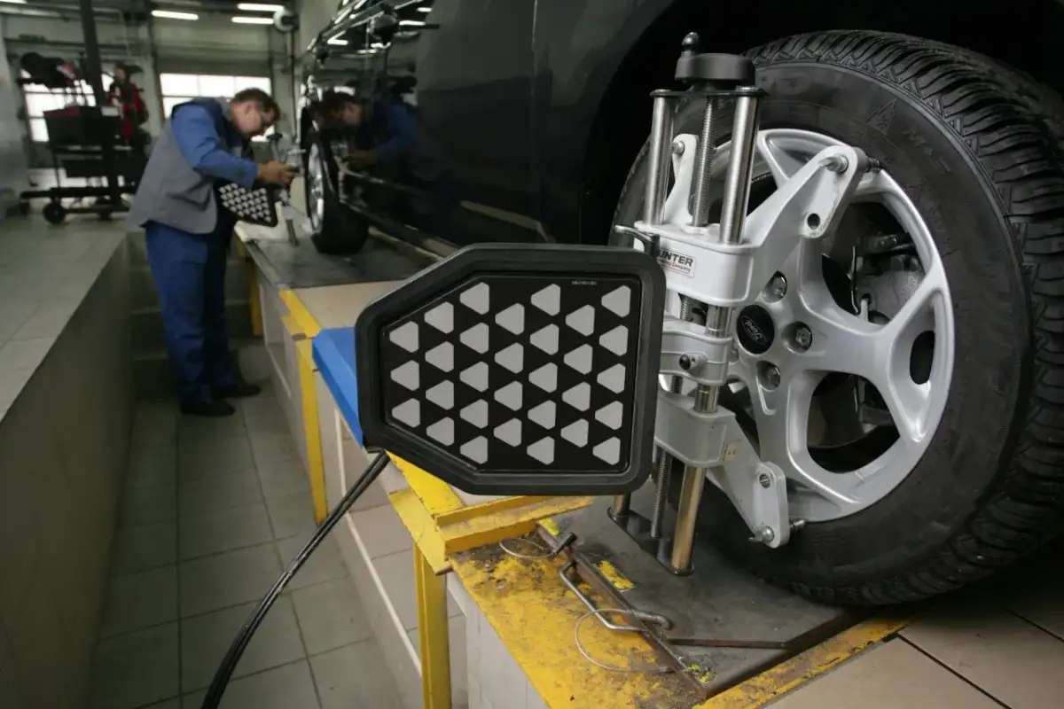 Mechanik ustawia tarczę zbieżności kół przy samochodzie.