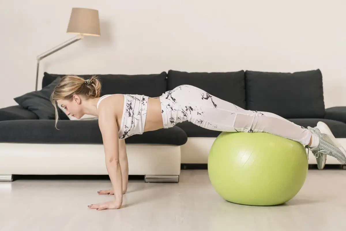 Kobieta wykonuje ćwiczenie na piłce gimnastycznej, które pomaga jak ćwiczyć na piłce żeby schudnąć.